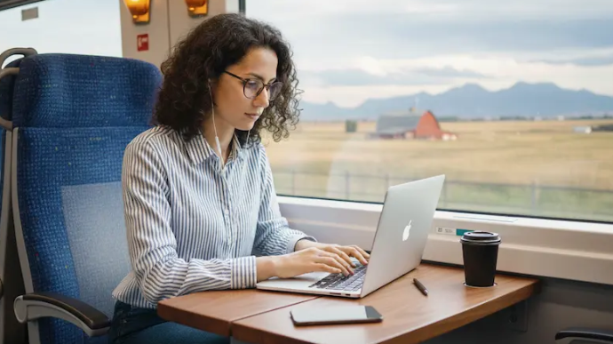 A woman is sitting on the train in front of her laptop, studying
